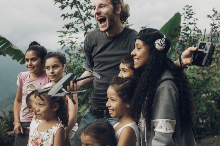 Jonathan met een groep lachende kinderen en een drone in Colombia