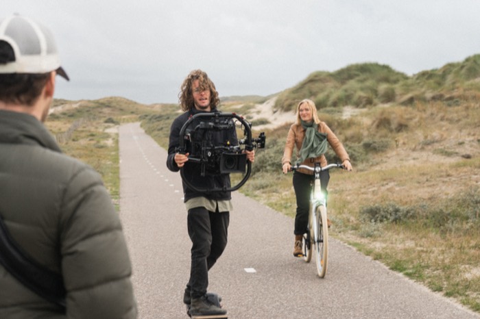 Jonathan filmt met een gimbal op een fietspad door de duinen